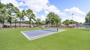 A tennis court surrounded by trees and a fence.